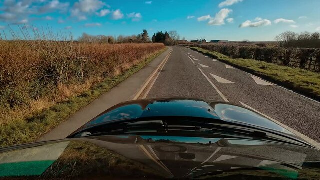 First person view, left-hand traffic, car driving in picturesque British countryside towards Leicester, Leicestershire, Great Britain, Europe. Road trip video SUV truck with bright, sunny, blue sky