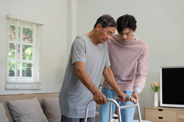Caring son assisting elderly father with walker in a bright living room, showcasing family support...