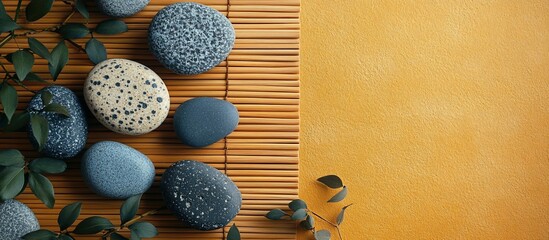 A serene arrangement of smooth stones on a bamboo mat with a warm yellow background