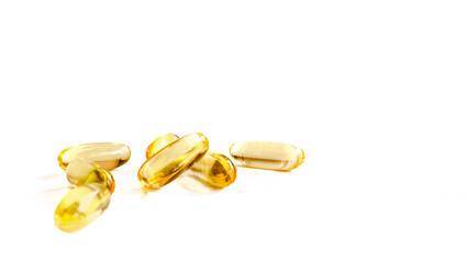 Golden yellow pills in spoon scattered on white background. Softgel capsule of food supplements fish oil omega 3 vitamin D3 vitamin E oil capsules on white background.