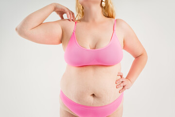 Fototapeta premium Fat woman in pink underwear on gray background, overweight female, obesity body, weight loss concept