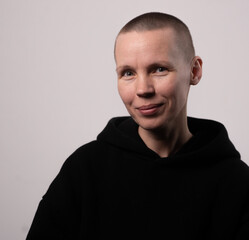 Female caucasian adult with buzz cut wearing black hoodie smiling