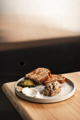 Rustic Sourdough with Smoked Fish Rillettes, Pickles, Mustard, and Whipped Cheese on a Neutral Ceramic Plate
