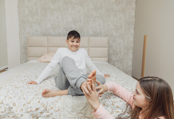 the children are wrapped in a blanket and tickling each other's heels on the bed. Family having fun...