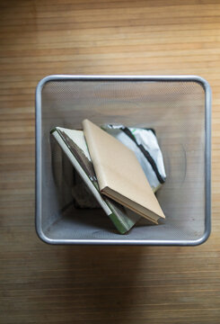 Top view of books in a metal mesh bin on a wooden floor