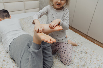 the children are wrapped in a blanket and tickling each other's heels on the bed. Family having fun...