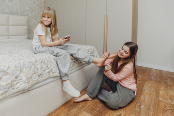 the children are wrapped in a blanket and tickling each other's heels on the bed. Family having fun...