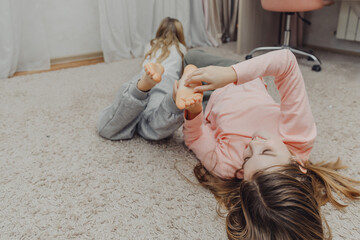 the children are wrapped in a blanket and tickling each other's heels on the bed. Family having fun...
