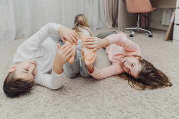 the children are wrapped in a blanket and tickling each other's heels on the bed. Family having fun...