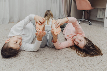 the children are wrapped in a blanket and tickling each other's heels on the bed. Family having fun...