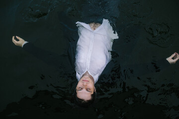 Man in Suit Floating on Dark Water with a Calm Expression