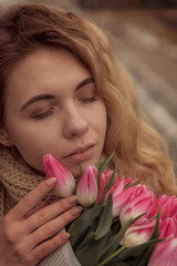 Close-up of a blonde with a bouquet of pink tulips.