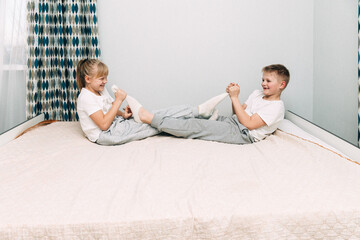 A little girl takes her brother's sock off and lightly tickles him. children laugh.