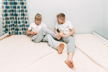 the children are wrapped in a blanket and tickling each other's heels on the bed. Family having fun...