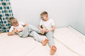 the children are wrapped in a blanket and tickling each other's heels on the bed. Family having fun...