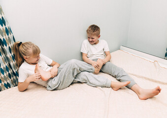 the children are wrapped in a blanket and tickling each other's heels on the bed. Family having fun...