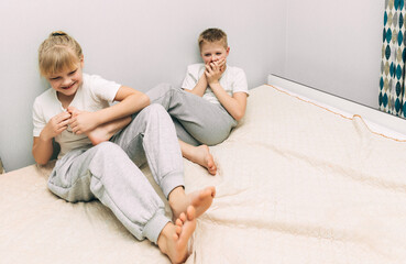 the children are wrapped in a blanket and tickling each other's heels on the bed. Family having fun...