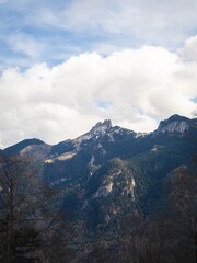 Fototapeta premium The Kampenwand mountain range in Bavaria, Germany, under a vibrant sky. Snow-dusted peaks rise above lush forested slopes, creating a breathtaking alpine view.