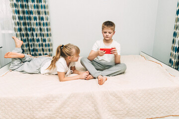 the children are wrapped in a blanket and tickling each other's heels on the bed. Family having fun...