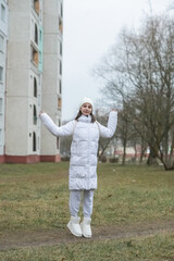 Portrait of a young beautiful dark-haired girl in light clothes on the street in early spring.