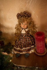 Cute vintage doll sits on a shelf near a Christmas tree