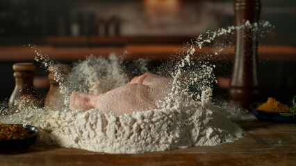 Freeze Motion of Falling Raw Chicken Leg into Flour . Closeup of Meat Preparation