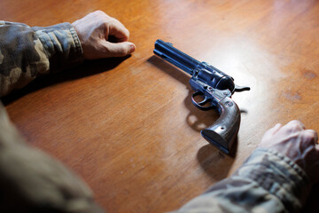 Soldier with PTSD contemplating suicide while looking at a gun on table