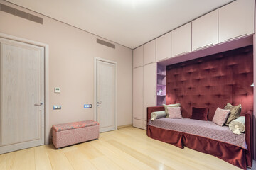 A cozy room for a teenager with pink decor. Built-in wardrobes, comfortable bed with pillows.