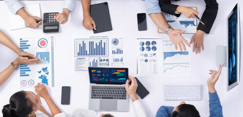 Top view analyst team utilizing BI Fintech to analyze financial data at table in meeting room....