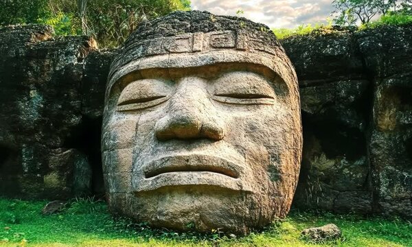 Giant Olmec head sculpture in jungle, travel and culture concept