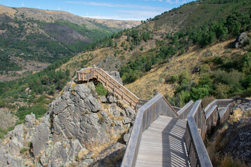 Wooden walkway in a portuguese valley. Mountains with forest and rocks. High view point scenic hiking trail. Active holiday explore nature. Trekking viewpoint. 
