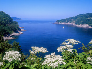 Fototapeta premium Serene Seascape: Blue Waves, Green Foliage, and Floral Beauty