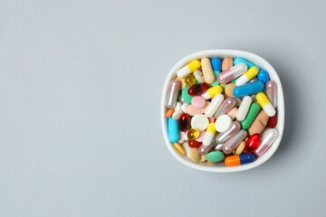Various pills in a bowl on gray background