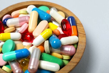 Various pills in a bowl on gray background