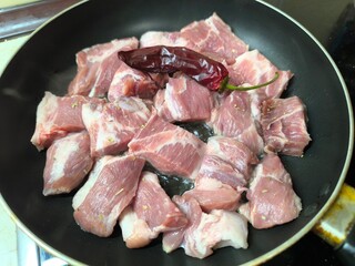 Pieces of meat are fried in a frying pan on the stove