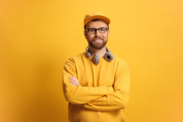 Fototapeta premium Man in a yellow sweatshirt and cap posing against a yellow background