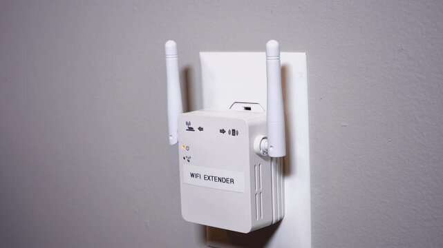 A close up shot of a man plugging in a typical WiFi extender into a household wall outlet. With simulated hotspot radio waves emanating from the device.  	