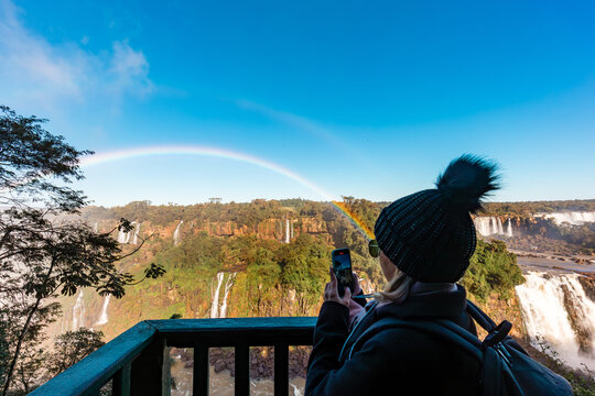Woman tourist filming the Iguazu Falls, border between Brazil and Argentina. - Powered by Adobe