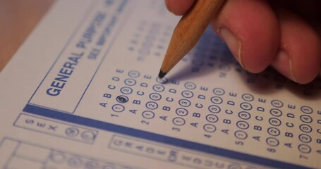 A close-up dolly shot of a student filling in the little bubble circles of a test paper.  	