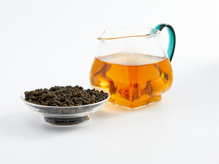 dry Chinese tea in a plate and next to it brewed in a teapot, photo on a white background