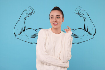 Beautiful young woman with drawing of strong arms behind her on light blue background