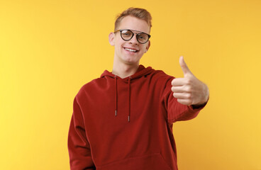 Fototapeta premium Happy man showing thumbs up on yellow background. Like gesture