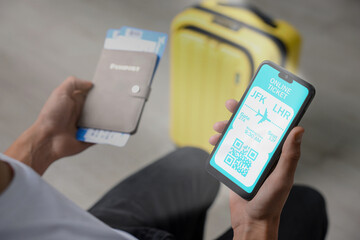 Tourist with passport, flight tickets and mobile phone indoors, above view. Online ticket with QR code on device screen