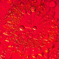 Bright red surface displays a stunning array of water and oil droplets, showcasing intricate patterns and vibrant colors under natural light