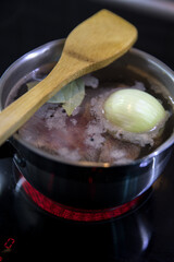 Meat, onion and bay leaf in a saucepan on the stove