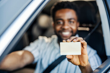Close up of black man's hand holding driver's license and showing it at the camera.