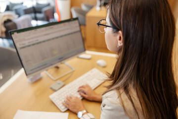 Rear view of car dealer typing on computer keyboard and filling up form at car showroom.