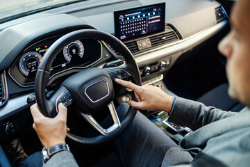 Cropped picture of a businessman's hands on a steering wheel in classy car.
