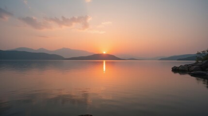 Obraz premium Tranquil Sunrise Over Serene Lake with Silhouetted Mountains