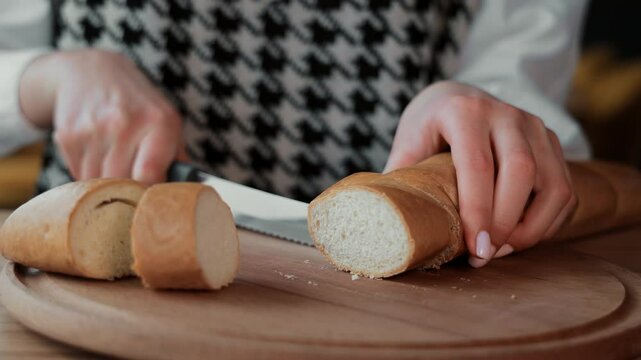 Woman slicing fresh bread on a wooden board, Close-up of a woman cutting a loaf of fresh bread into slices on a wooden board.